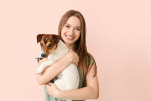 Young woman with cute dog on color background
